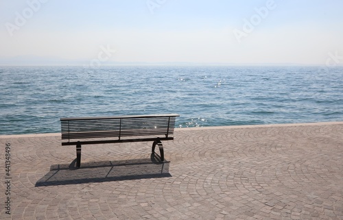 lonely bench on the shore with the placid water symbol of tranquility and relaxation
