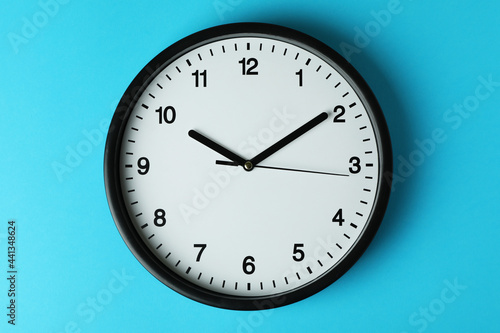 Standard black office clock on blue background