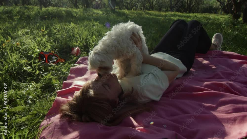 Puppy Cuddling With Owner, Young Woman, Relaxing On The Grass In Park. SLOW MOTION. Dog enjoying sunny sunset outdoors, hugging with smiling girl. Pet and owner love. Puppy Cuddling With Owner, Young Woman, Relaxing On The Grass In Park. SLOW MOTION. Dog enjoying sunny sunset outdoors, hugging with smiling girl. Pet and owner love.