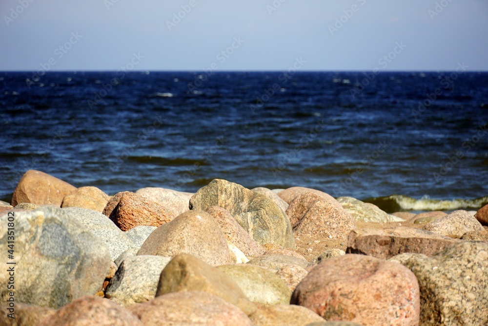 A close up of a rock next to water. Stone beach. Gulf of Finland. Blue water. Sea. High quality photo