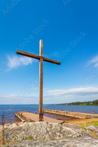 church cross on a rock on a lakeshore