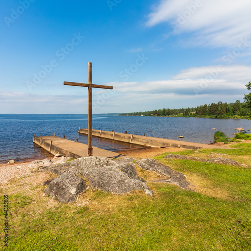 church cross on a rock on a lakeshore