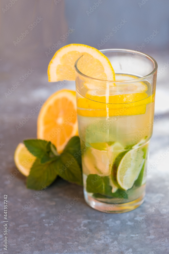 Fototapeta premium Lemonade with lemon, lime and mint. Illuminating summer drink with ice. Bright mojito in a glass.