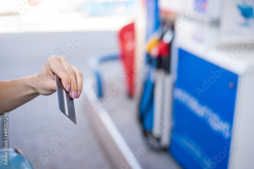 A woman pays with a credit card while refueling a car
