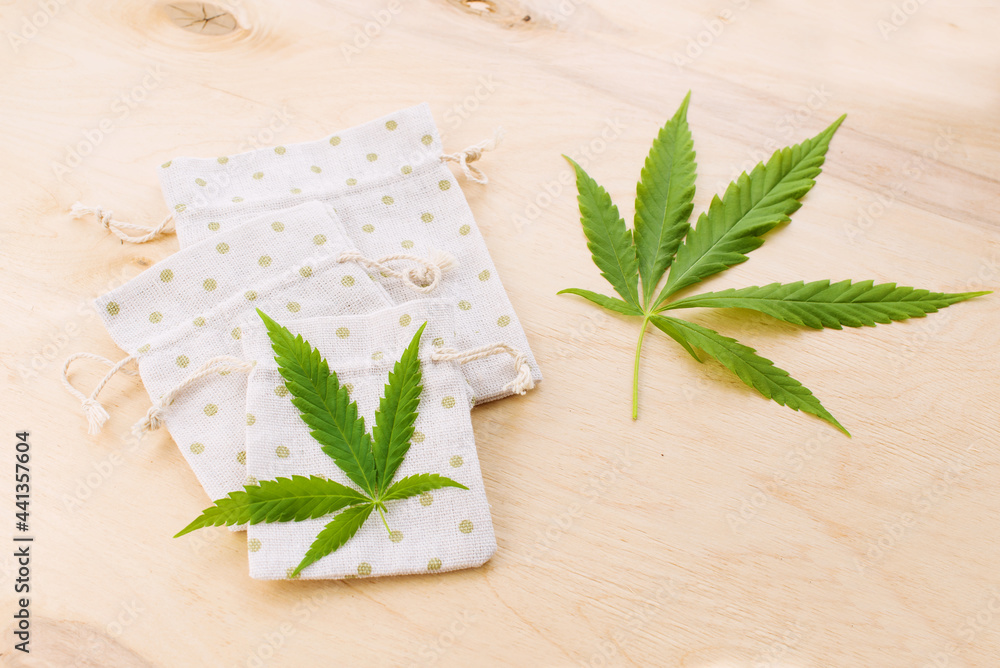 Set of textile products made from nature fiber such as hemp, cannabis leaf and seeds. Handmade fabric mini pouches, eco friendly and sustainable hemp bags on wooden background. Top view, flat lay