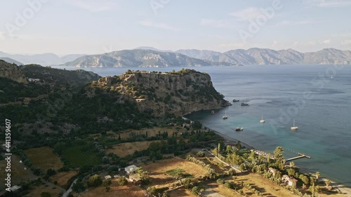 Aerial view of the Aegean sea with mountains and coastline with sailboats in the background of the island