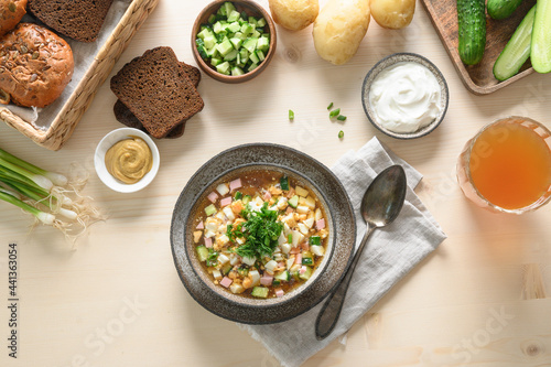 Summer homemade freshness cold soup Okroshka with kvass, raw chopped vegetables, eggs and ingredients on a light wooden background. View from above. Russian and Ukrainian cuisine. Home cooking.