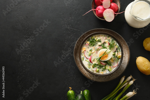 Summer freshness Russian cold soup Okroshka with kefir or airan and raw vegetables ingredients on a black background. View from above. Copy space.