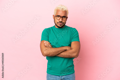 Young Colombian handsome man isolated on pink background feeling upset