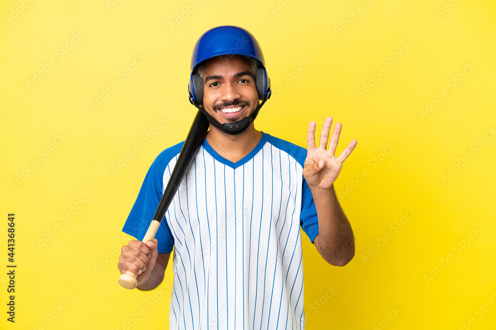 Young Colombian latin man playing baseball isolated on yellow background happy and counting four with fingers