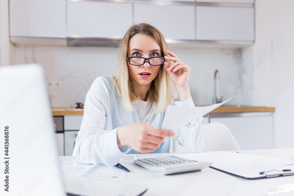 young female housewife sitting a table in house kitchen an incomprehensible deal with paperwork bills and loans. Woman is exhausted and frustrated with documents of enterprise or family budget at home young female housewife sitting a table in house kitchen an incomprehensible deal with paperwork bills and loans. Woman is exhausted and frustrated with documents of enterprise or family budget at home