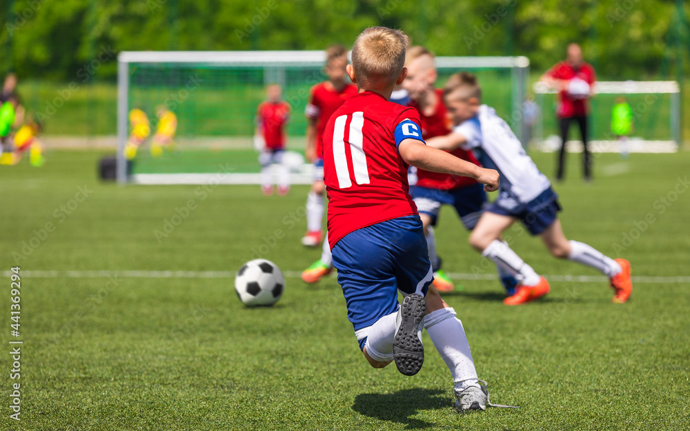 Group of Soccer Boys in Red Uniforms Playing School Tournament Game. Child Football Team Captain Running Ball and Compete in a Duel Group of Soccer Boys in Red Uniforms Playing School Tournament Game. Child Football Team Captain Running Ball and Compete in a Duel