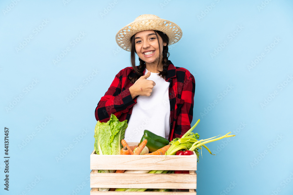 Young farmer Woman holding fresh vegetables in a wooden basket giving a thumbs up gesture