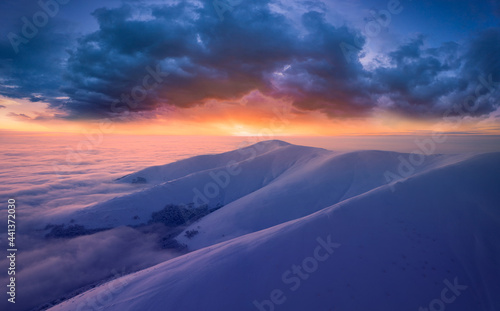 Dawn over the tops of snow-capped mountains view from a drone