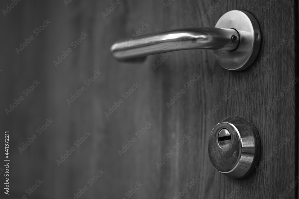 A door with a chrome handle and lock hole. Black and white photo A door with a chrome handle and lock hole. Black and white photo