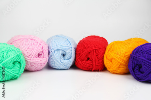 A lot of multi-colored wool balls of knitted yarn lie in a row close-up on a white background. The concept of handmade, needlework and needlework. Top view. Flatley. A place to copy.