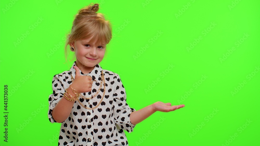 Funny playful blonde kid child showing thumbs up and pointing empty place, advertising area for commercial text, copy space for goods promotion on chroma key background. Cute teenager children girl Funny playful blonde kid child showing thumbs up and pointing empty place, advertising area for commercial text, copy space for goods promotion on chroma key background. Cute teenager children girl