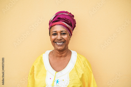 Happy senior african woman wearing traditional dress looking at camera - Focus on face