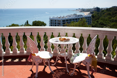 Chairs and a table are on the veranda with stunning sea view. Coffee, cakes and biscuits on a plate. Bulgaria, Golden Sands
