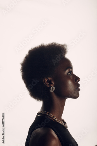 Close up vertical profile portrait of african american woman with afro hairstyle on white studio background.
