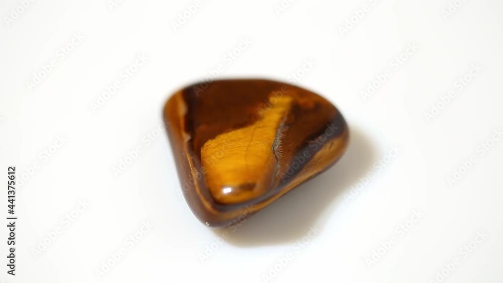 Tiger's Eye flat gemstone rotating on a white background Tiger's Eye flat gemstone rotating on a white background