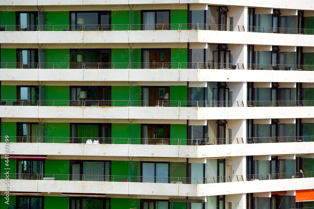 Monotonous facade of a high-rise building with long balconies and green panels to cover the front sides Monotonous facade of a high-rise building with long balconies and green panels to cover the front sides