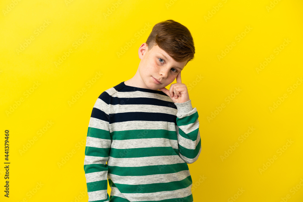 Little redhead boy isolated on yellow background thinking an idea Little redhead boy isolated on yellow background thinking an idea