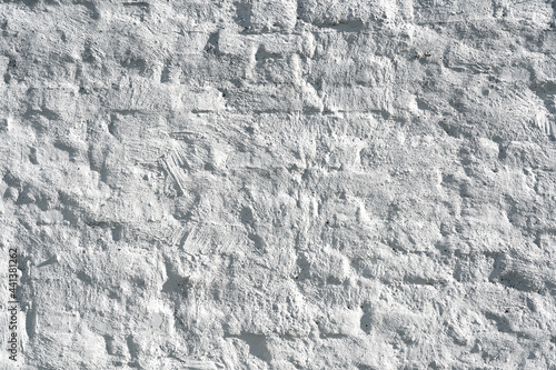 Fragment of an old wall with brickwork not too evenly laid. Crookedly laid bricks show through a thin layer of uneven plaster and paint. Background. Texture.