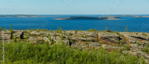 Panorama of seascape with rocks and boulders in foreground. White Sea, Russia, view of archipelago of Kuzova from a high point. Islands, sea, sky and rocky coast in northern latitudes on sunny day.