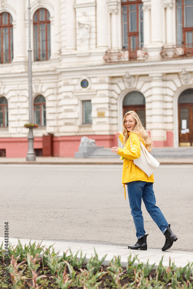 Girl in yellow raincoat with eco-beek walks through the city