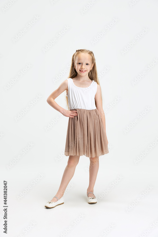 Beautiful little girl in modern stylish dress posing isolated on white studio background. Happy childhood concept. Beautiful little girl in modern stylish dress posing isolated on white studio background. Happy childhood concept.