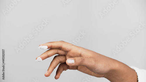 Cropped view of cosmetic cream on fingers of african american woman isolated on grey