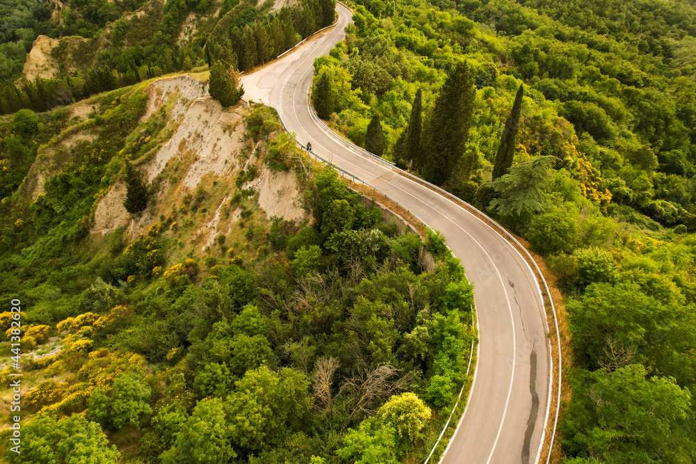 Beautiful idyllic summer landscape of Toscana with mediterranean plants, hills, trees, forests and fields. Sunny evening or morning in Italy. Vacation, recreation mood. Road in hills of Tuscany 
