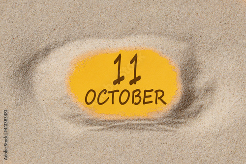 October 11. 11th day of the month, calendar date. Hole in sand. Yellow background is visible through hole. Autumn month, day of the year concept photo