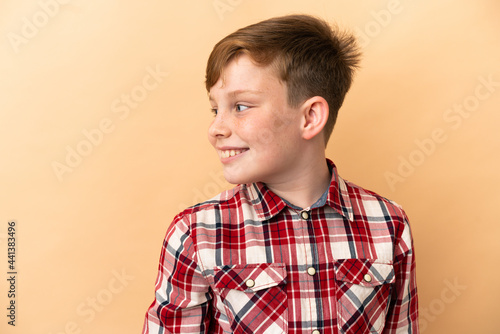 Little redhead boy isolated on beige background