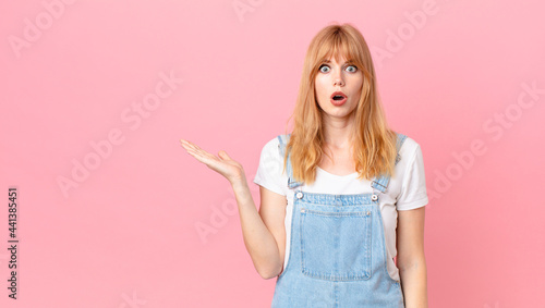Εκτύπωση καμβά pretty red head woman looking surprised and shocked, with jaw dropped holding an