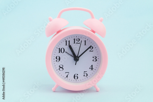 Pink alarm clock on blue background.	