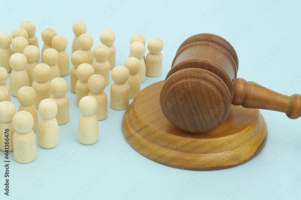 Many wooden figures of people and judge gavel. on blue background.	