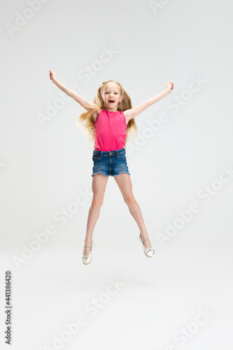 Beautiful little girl in casual clothes jumping isolated on white studio background. Happy childhood concept.