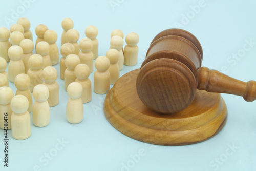 Many wooden figures of people and judge gavel. on blue background. 