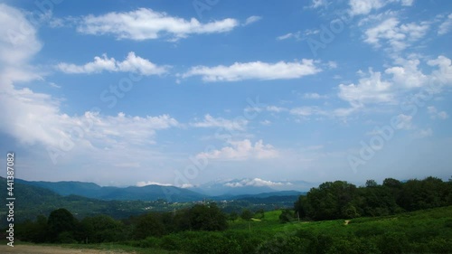 Natural summer landscape filmed in time lapse. Beautiful clouds float in the blue sky. Around the hills with tea plantations. Mists rise over the mountains in the distance.