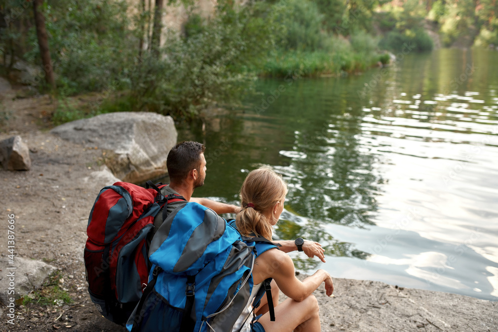 Young caucasian pair sitting on log near lake Young caucasian pair sitting on log near lake