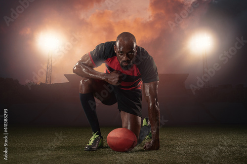 Professional male rugby player posing isolated on stadium background. African fit athlete preparing for match