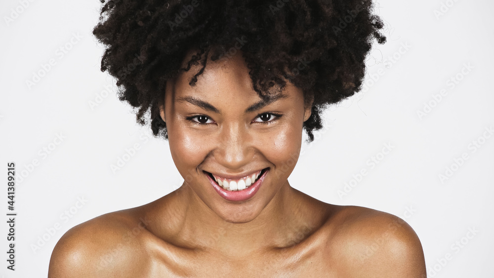 Cheerful african american woman with naked shoulders looking at camera isolated on grey Cheerful african american woman with naked shoulders looking at camera isolated on grey