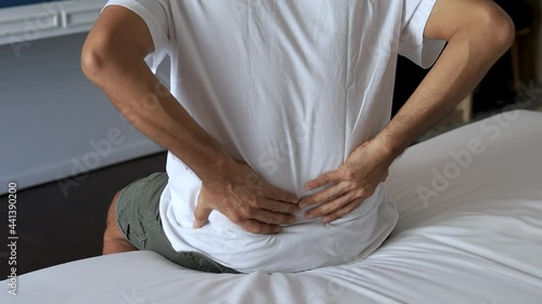young man suffering from back pain on the bed, healthcare and problem concept