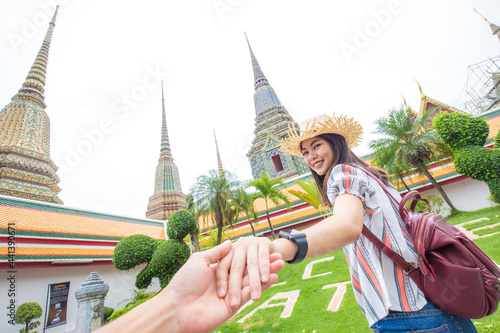 Asian women leading man hand follow travel in buddhist temple couple relationship