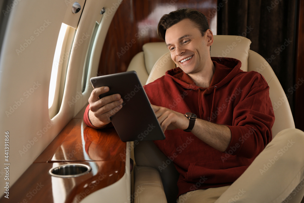 © New Africa - Young man using tablet in airplane during flight