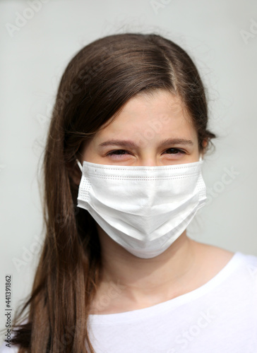 girl with long brown hair with white mask to protect herself from coronavirus