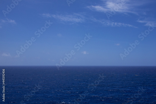 An ocean scene. The aquatic seascape is shot from an elevated position out into the wide open sea and sky