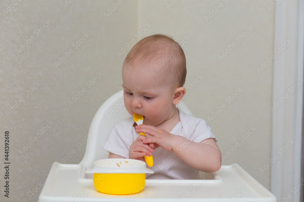 the first feeding. Baby puree from a jar. A small child sits in a highchair and eats. the first feeding. Baby puree from a jar. A small child sits in a highchair and eats.
